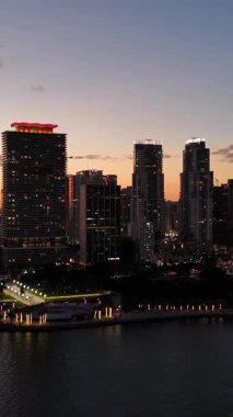 Akşam gökyüzünde parlayan uzun gökdelenlerle çarpıcı bir gece şehri manzarası, alacakaranlıkta kentsel ışıkların güzelliğini yakalıyor..