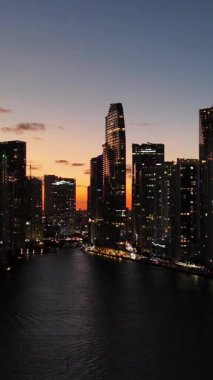Alacakaranlıkta Miami şehir merkezindeki modern binaları, şehir ışıklarını, şehir siluetini ve akşam atmosferini gösteren insansız hava aracı görüntüsü..