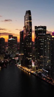 Alacakaranlıkta Miami iş dünyasının güzel hava görüntüleri. Gökdelenlerin ışıklarla parıldadığını ve büyük, modern bir şehrin canlı gece hayatını gösteriyor..
