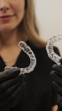 Gülümseyen bir insanın net bir ortodontik hizalayıcıyı nasıl sığdıracağını gösterirken, diş hizalama ve ağız bakımı için modern saydam diş tepsilerinin uygun kullanımı ve konforunu gösterirken yakın çekimi.