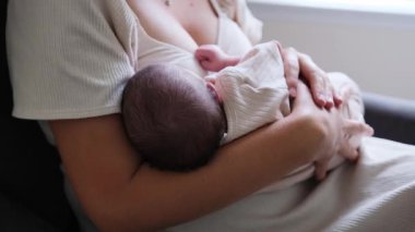 Yeni doğmuş bebeğini emziren genç bir annenin sakin bir yuva ortamında yakın plan çekimini bitirmek. Doğal ışık ve sıcak tonlar anneliğin derin duygusal bağını ve rahatlığını vurgular..