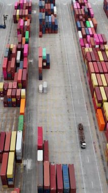 Hava görüntüsü canlı ve yoğun bir nakliye konteynır deposu gösteriyor. Renkli kargo düzenli bir şekilde yerleştirilmiş.