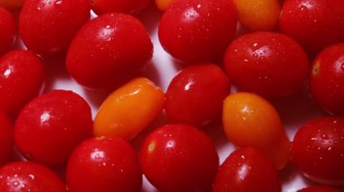 Çeri domateslerinin yakın çekim makro görüntüsü, sarı domates yavaşça dönüyor, pürüzsüz ciltleri, şekilleri ve canlı kırmızı ve sarı renkleri ortaya çıkıyor..