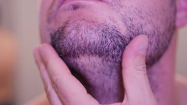 Traş olmadan önce sakalını elleriyle inceleyen bir adamın yakın çekim görüntüleri. Yüksek çözünürlüklü erkekler için günlük bakım, cilt bakımı ve kişisel bakım kavramı.