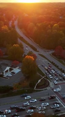 İnsansız hava aracı görüntüleri renkli sonbahar ağaçları arasında giden arabaları gösteriyor. Amerikan banliyösünde altın ışık ve sıcak atmosfer.