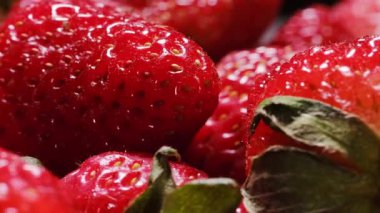 Olgun çileklerin yakın çekim makro görüntüleri sulu kırmızı doku, tohumlar ve yeşil yaprakları gösteriyor. Sağlıklı beslenme, yaz ve doğal gıda temaları için taze organik meyve konsepti.