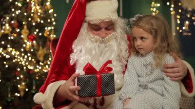 Noel Baba kıza hediye verir, kız Noel Baba 'dan güzel bir hediye alır ışıltılı bir bayramın ortasında