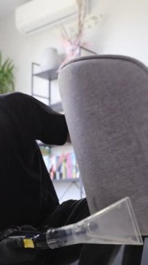 Gri kumaş bir sandalyenin arka tarafını temizleyen bir çıkartma aracının yakın plan görüntüsü.