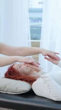 Yumuşak ışık, sakinlik ve dikkatli bir odak ile dolu parlak huzurlu bir odada enerji iyileştirme seansı yapan bir kadının yakın çekimi..