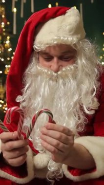 Noel Baba elinde iki baston şeker tutuyor ve sıcak bir Noel arifesinde bayram ziyafeti hazırlıyor..