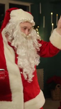 Noel Baba süslü bir Noel ağacının yanında neşeyle dans ederek eğlenceli ve şenlikli bir tatil ortamı yaratıyor. Sıcak ve büyülü Noel anı.