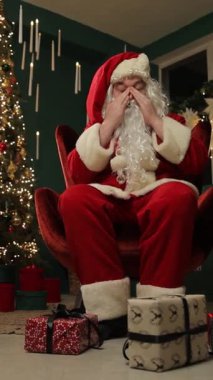 Noel Baba 'nın koltukta oturup festival odasında yüzünü ovalamasından bıktım. Dikey video.