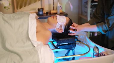 Spa terapisti, sakin ve rahatlatıcı bir spa tedavisi sırasında hastaların saçlarını yıkar ve nazik bir baş bakımı sağlar..