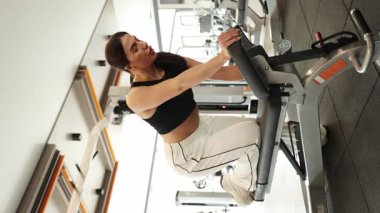 Bir kadın modern bir spor salonunda dambıllarla egzersiz yapıyor..