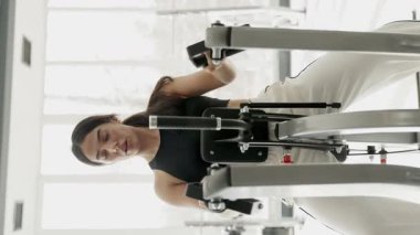 Siyah spor bluzlu bir kadın spor makinesinde karın çatırdatma hareketi yapıyor..