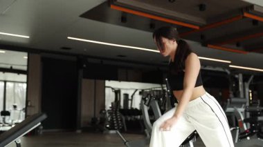 Modern bir spor salonunda antrenmandan sonra esneme hareketleri yapan kadın..