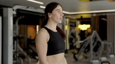 Modern bir spor salonunda ağırlık kaldıran bir kadın..