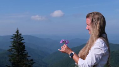 Mor çiçekli bir kadın dağ sırtında manzaralı bir manzarayla.