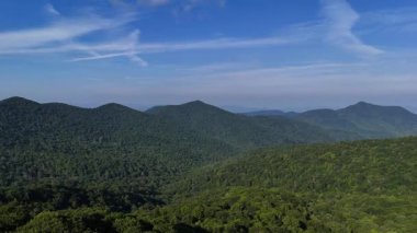 Parlak güneşli bir günde mavi gökyüzünün altında, yumuşak bulutlu yemyeşil dağlar ortaya çıkar ve ABD 'de canlı ve canlı bir doğa sahnesi yaratır..