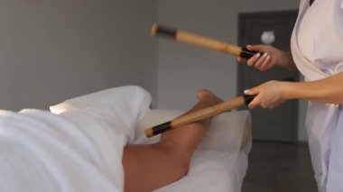 Masaj terapisti müşterinin bacaklarına bambu çubuğu masajı yapar. Ritmik tıkırtı ve yuvarlanma gevşeme ve dolaşım için eşsiz bir tedavi tekniği yaratır..