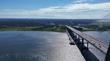 Ravenel Köprüsü 'nün uzaktan görülebilen Charleston Güney Carolina ve kıyı şeridi boyunca uzanan insansız hava aracı görüntüsü. Parlak güneş ışığı suyu yansıtır ve temiz, modern bir manzara yaratır..