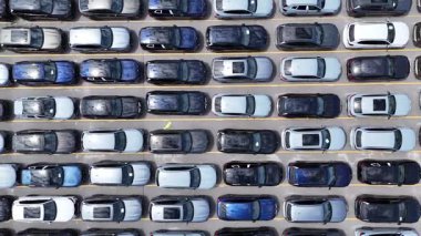 Dikey bir drone, düz sıra dizilmiş park halindeki yeni arabaların yoğun düzenini yakalıyor. Tekrarlanan yapı, endüstriyel ve lojistik temalar için ideal güçlü bir otomotiv modeli oluşturur..