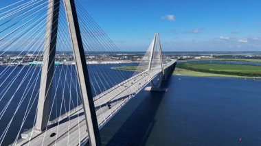 Arthur Ravenel Jr. Köprüsü 'nün Charleston Güney Carolina' daki uzun hava aracı görüntüsü, sakin su boyunca uzanan uzun sütunlarını ve süspansiyon kablolarını temiz ve simetrik bir şekilde gösteriyor..
