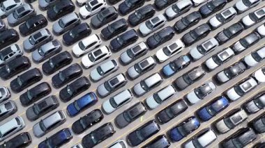 İnsansız hava aracı görüntüleri bir otomotiv dağıtım tesisinde sıkıca dizilmiş yeni araçları gösteriyor. Lojistik ve ulaşım temaları için ideal.