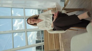 Bir kadın psikoloğun, açık bir günde geniş pencerelerin arka planına karşı bir müşteriyle yaptığı istişare sırasında çekilmiş dikey videosu. Modern profesyonel psikolojik danışmanlık. İlahi oturum