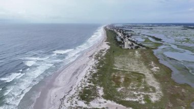 Okyanus dalgaları ve kumlu plajlarla dolu güzel bir sahil boyunca dramatik bir hava perspektifi uçuyor.