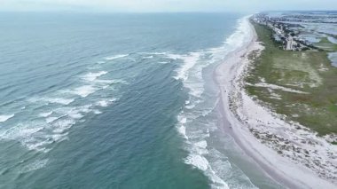 Aerial drone footage of a beautiful coastline with gentle ocean waves breaking on a sandy beach