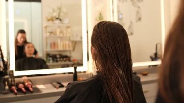 Profesyonel kuaför, güzellik salonunda stil yapmadan önce müşterilerini uzun ıslak saçlarıyla tarıyor.