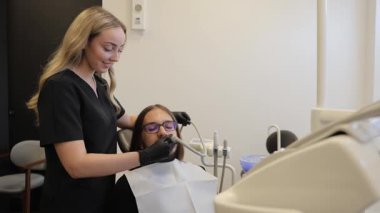 Diş hekimi klinikteki bir erkek hastada diş beyazlatma prosedürü için ultraviyole lamba kullanıyor.