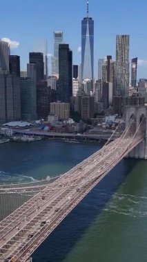 Güzel Brooklyn Köprüsü 'nün dikey videosu canlı New York şehrinin silueti tarafından çerçevelenmiştir. ABD