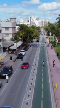Okyanus Yolu 'nun hava manzarası renkli sanat deco otelleri, palmiye çizgili sokaklar ve tropik güneş ışığında trafiği gösteriyor. Dikey video.