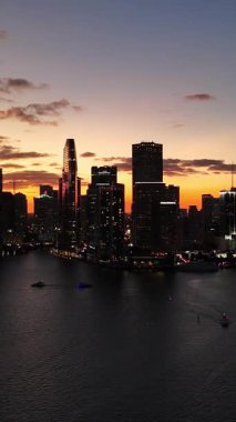 Miami 'nin turuncu ve mor gökyüzü sakin körfez suları ve yüksek ufuk çizgisine yansıyan gündoğumu manzarası. Dikey video.