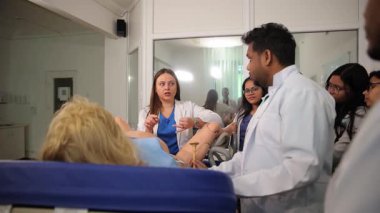 Profesör, çeşitli tıp öğrencilerine doğum mankeni kullanarak doğum yapmayı öğretiyor.