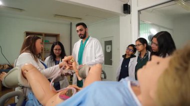 Bir grup üniversite öğrencisine doğum simülatörü kullanarak doğum eğitimi veren bir tıp profesörü.