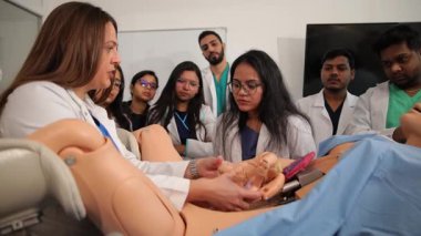 Genç tıp öğrencileri, doğum simülatörü mankeni kullanarak bir profesörden çocuk doğurmayı öğreniyorlar.