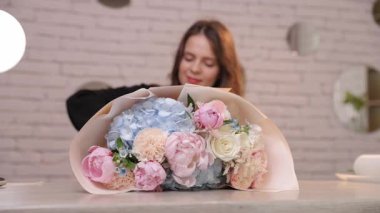 Genç bayan çiçekçi şakayık, gül ve ortanca desenli taze pastel bir buket hazırlıyor.