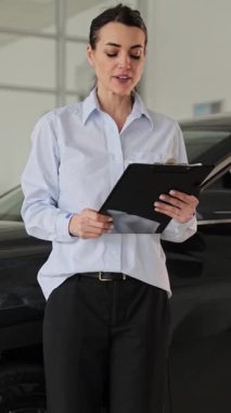 Kendine güvenen kadın araba galerisi müdürü başarılı bir satışı mutlu bir jestle kutluyor.