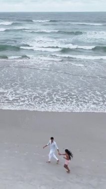 Tatilleri sırasında deniz kenarında yalınayak yürüyen genç bir çiftin güzel hava manzarası.