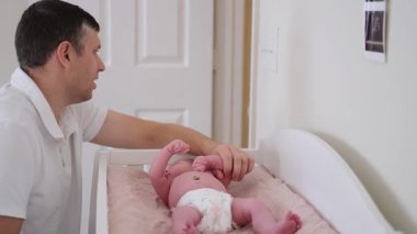 Genç baba ve oğlu, bebek odasında soyunma masasında yatan yeni doğmuş bir kıza hayran.