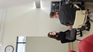 Modern bir klinikte erkek dişçi kadın bir hastaya danışıyor, ekranda çene röntgeni gösteriyor