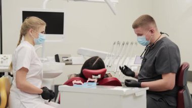 Modern bir klinikte çene modeli kullanan bir kadın hastaya danışmanlık yapan profesyonel erkek dişçi.