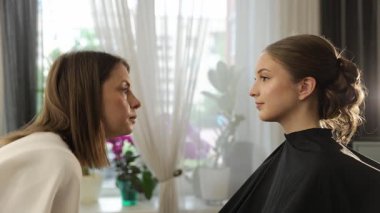 Profesyonel güzellik uzmanı bir güzellik salonunda genç bir kadının göz kapağına takma kirpik takıyor.