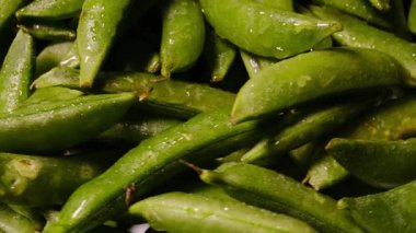 Taze yıkanmış yeşil edamame soya fasulyesi kabukları ve su damlacıkları yiyecek arka planında dönüyor.