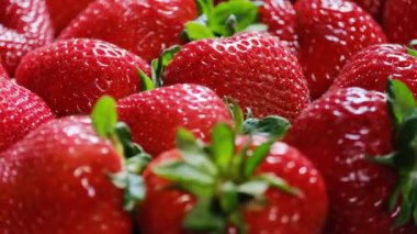 Sulu kırmızı olgun çilekler güzel bir yakın plan çekimde dönüyor, taze meyvelerin detaylarını gösteriyor.
