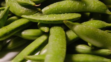 Beyaz arka planda dönen ıslak ve taze bezelyeler sağlıklı beslenmeyi gösteriyor.