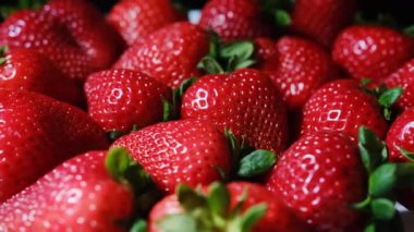 Taze, olgun ve sulu çileklerin yakın plan görüntüsü yavaşça dönüyor, canlı renklerini sergiliyor